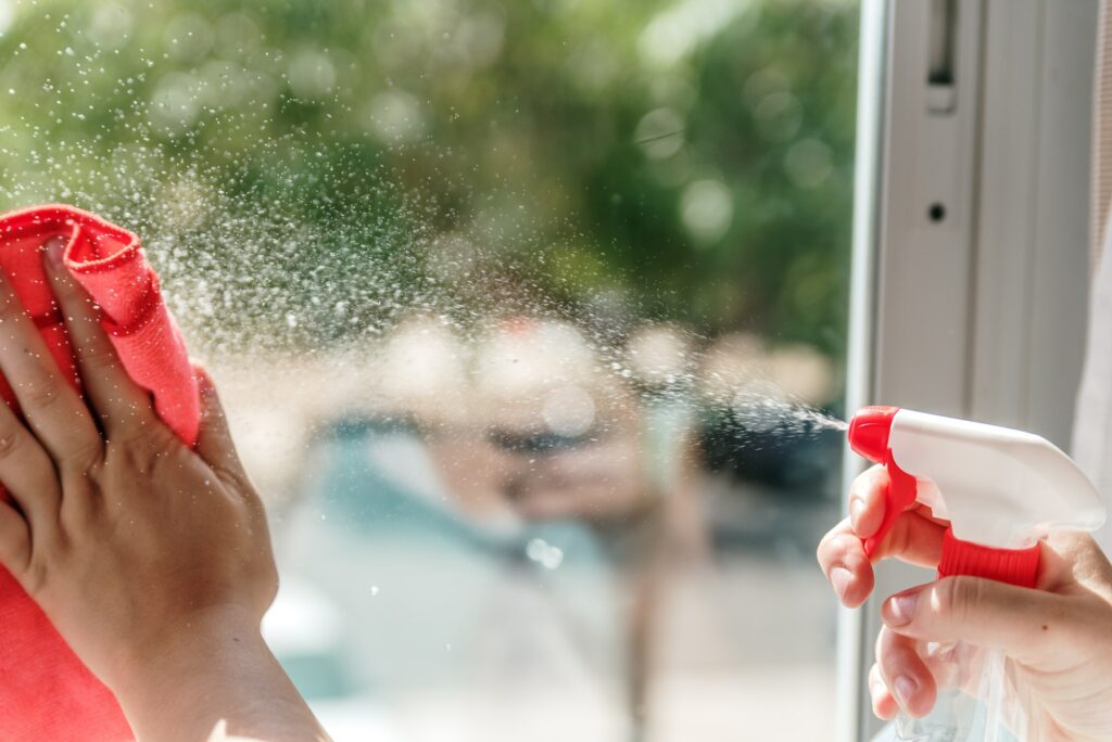 Woman's hand cleaning a window pane with window cleaning solution.